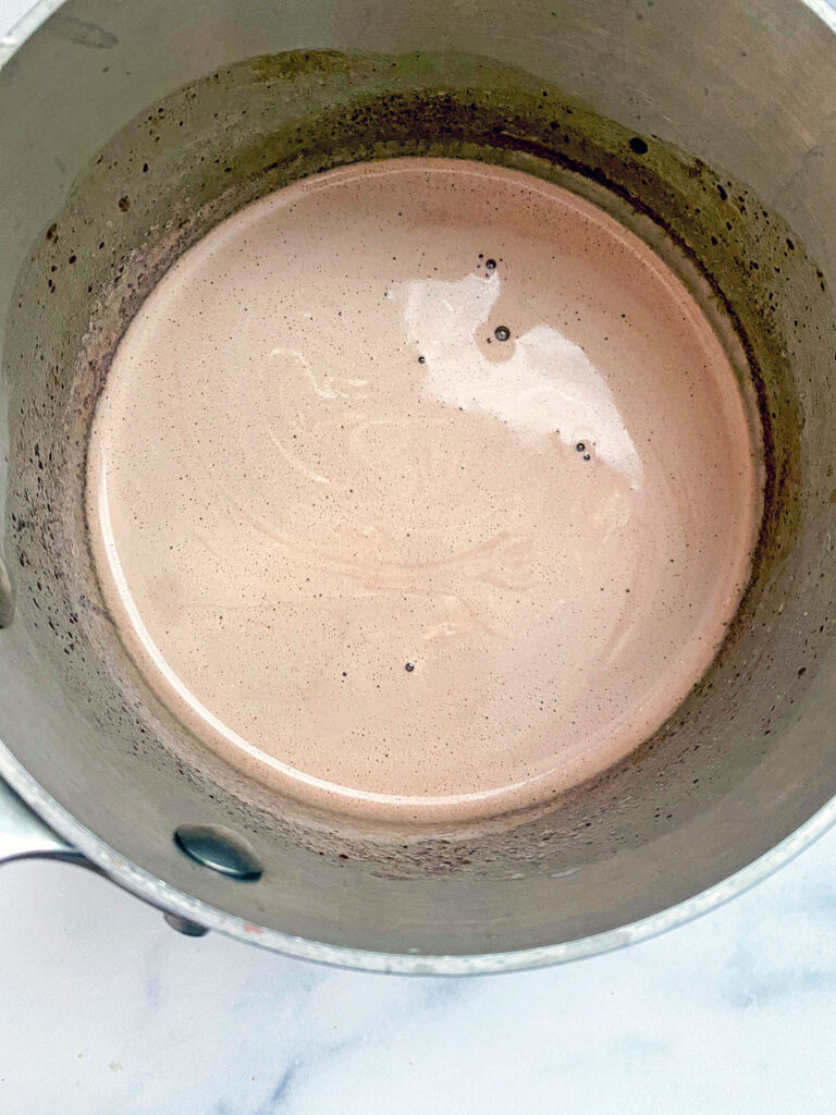 Overhead view of homemade hot chocolate with marshmallow fluff mixed in in saucepan.