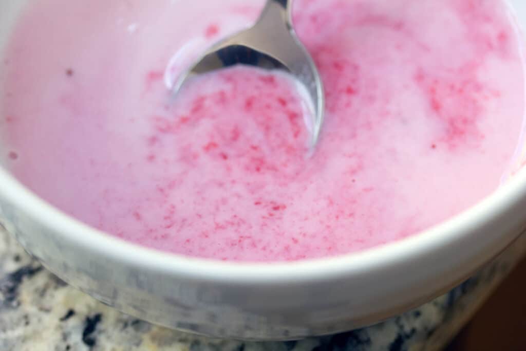 Homemade strawberry milk in a bowl with a spoon