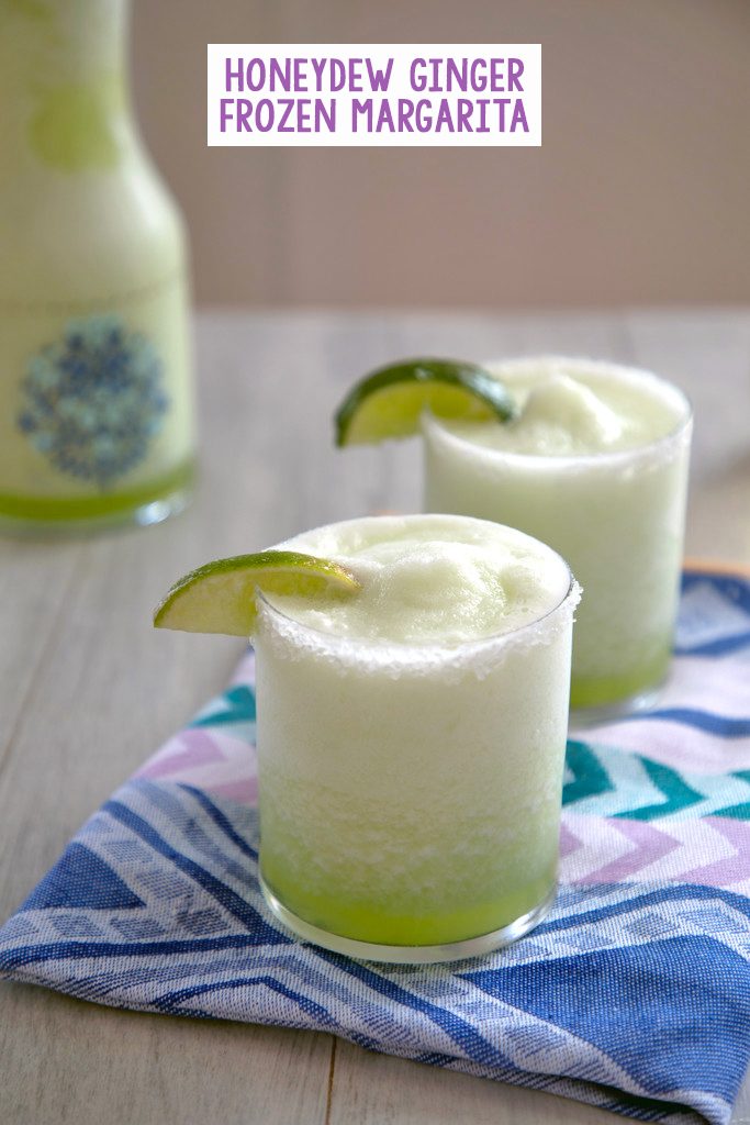 Head-on view of two bright green honeydew margaritas with lime wedge garnish on a colorful napkin with pitcher of margaritas in the background and recipe title at top