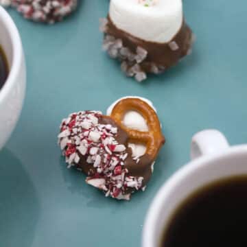 Closeup view of a pretzel bite filled with marshmallow and coated in chocolate and crushed peppermint.