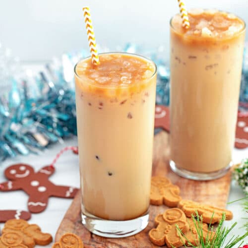 Landscape view of two ice gingerbread lattes on a wooden board with gingerbread men all around