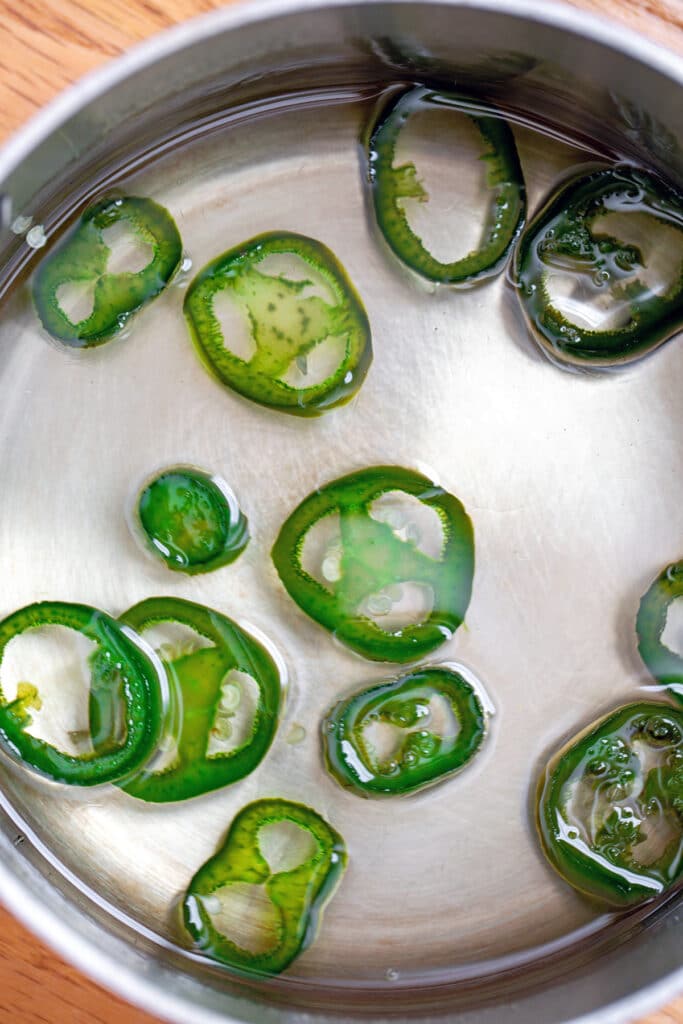 Sliced jalapeños that have been simmering in sugar water mixture and thickened into syrup