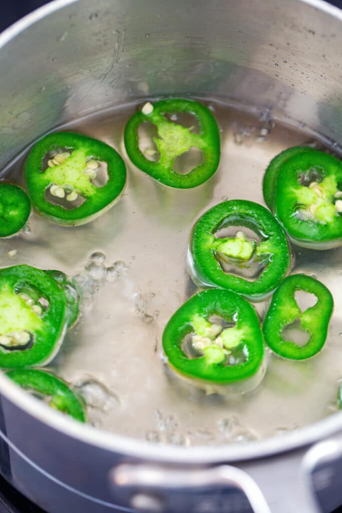 Sliced jalapeño peppers simmering in sugar water