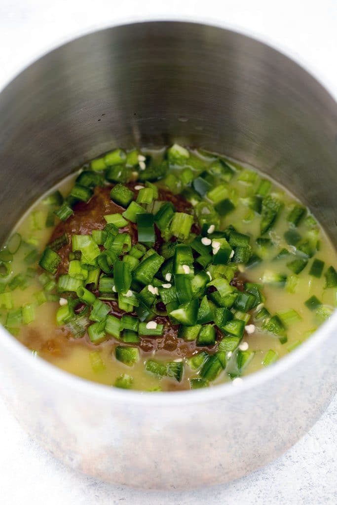 Orange marmalade, orange juice, chopped scallions, and diced jalapeño in saucepan ready to be heated for orange marmalade syrup