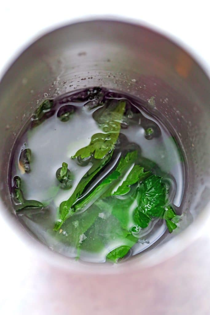 Overhead view of cocktail shaker with lemon and lime juice and parsley for jalapeño martini