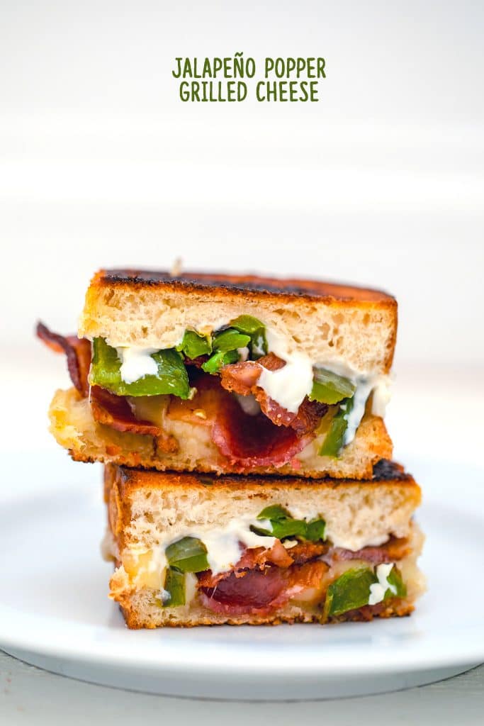 Head-on view of two halves of a jalapeño popper grilled cheese sandwich stacked on top of each other on a white plate with "Jalapeño Popper Grilled Cheese" text at top