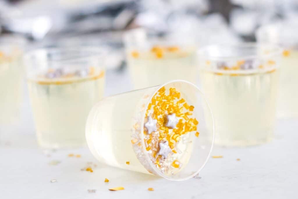 Champagne jello shots in little cups with gold and star sprinkles