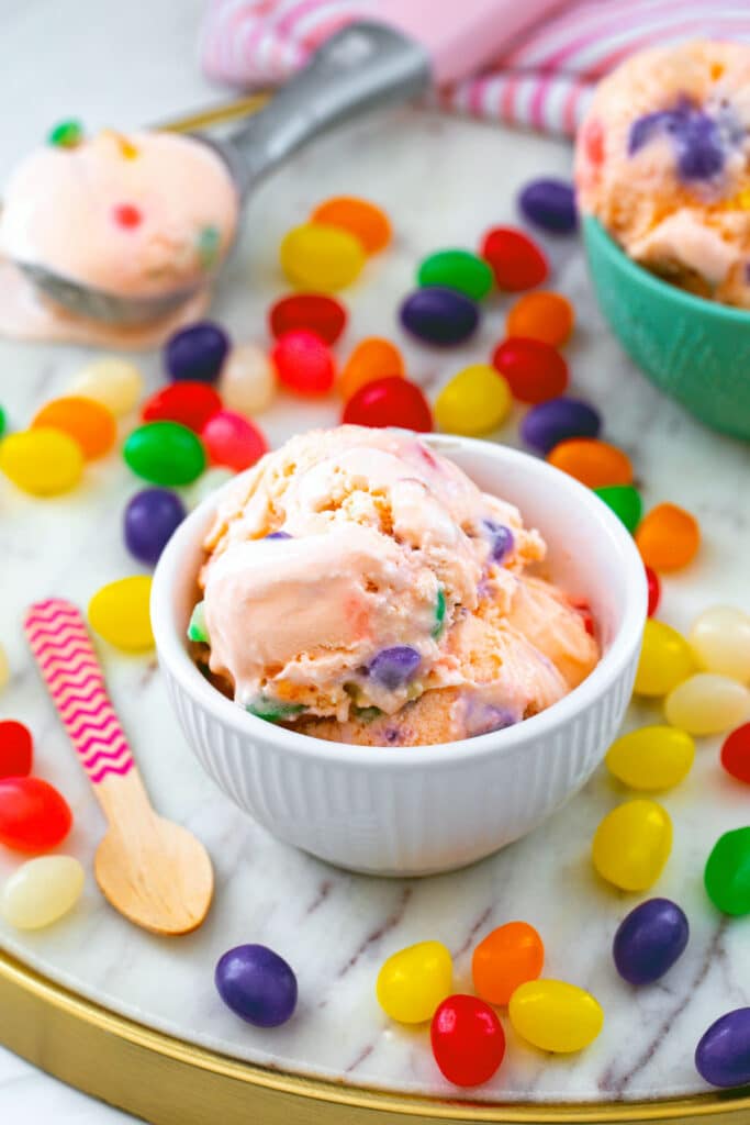 Bowl of jelly bean ice cream with scoop of ice cream and second bowl in background and jelly beans all around.