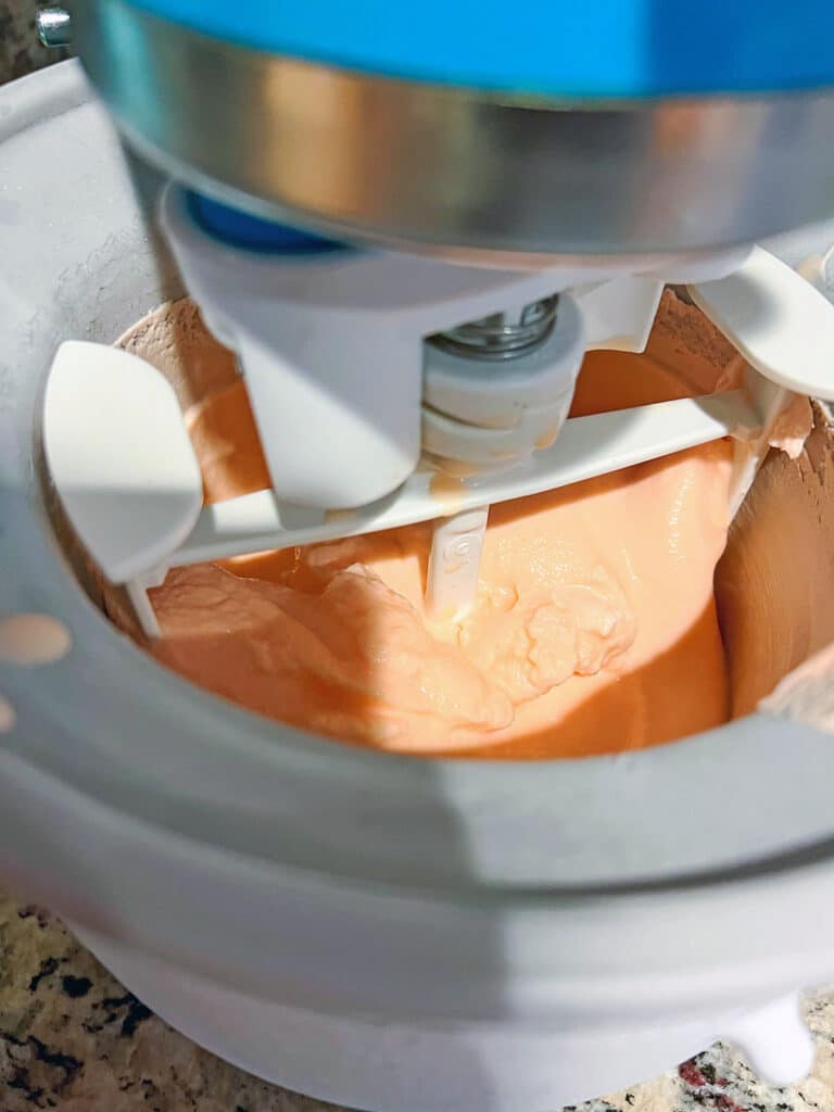 Orange colored ice cream processing in ice cream maker.