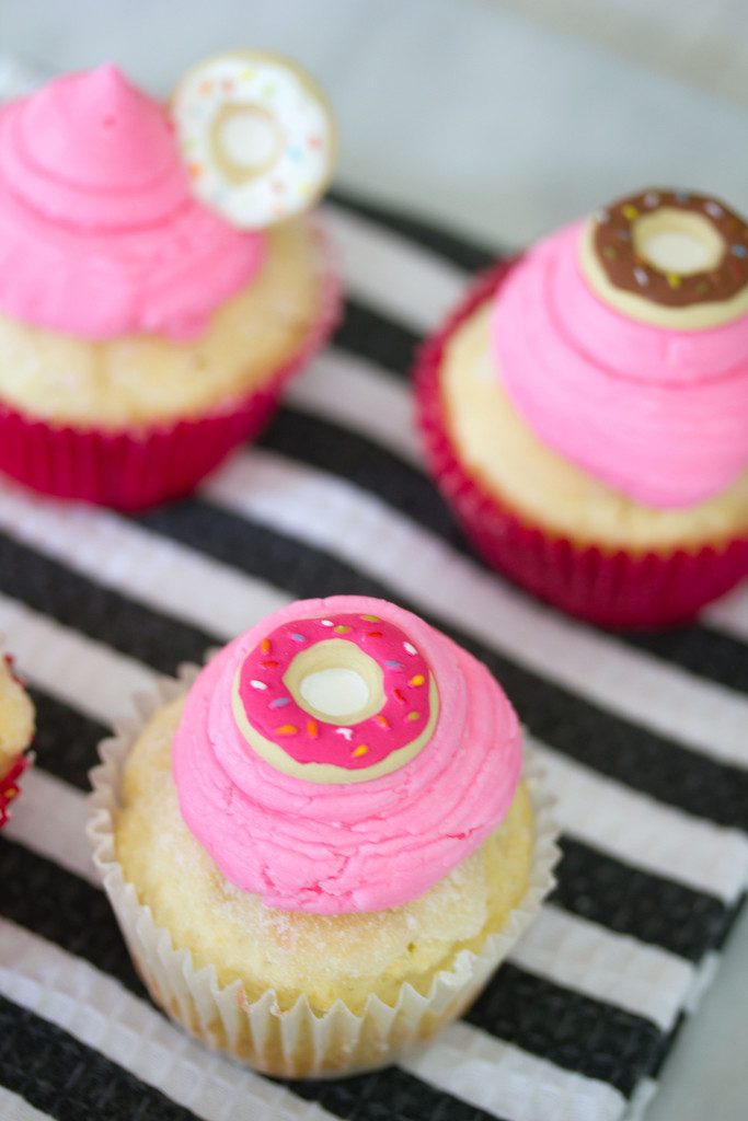 Overhead view of multiple jelly doughnut cupcakes topped with pink buttercream and mini donut icing toppers