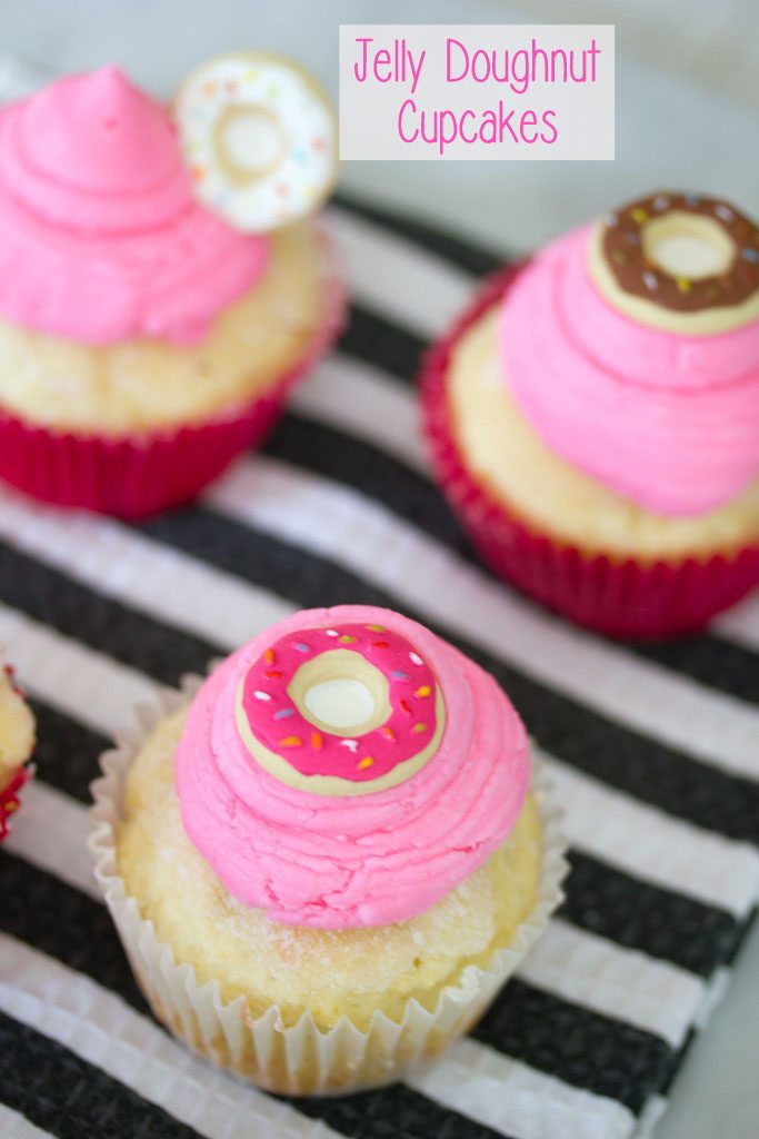 Overhead view of multiple jelly doughnut cupcakes topped with pink buttercream and mini donut icing toppers with recipe title at top