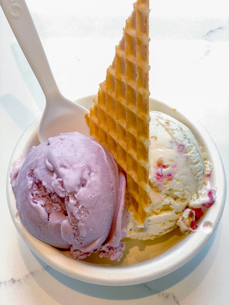 Overhead view of Jeni's Brambleberry and Wildberry Lavender Ice Cream in a bowl with a pieces of waffle cone