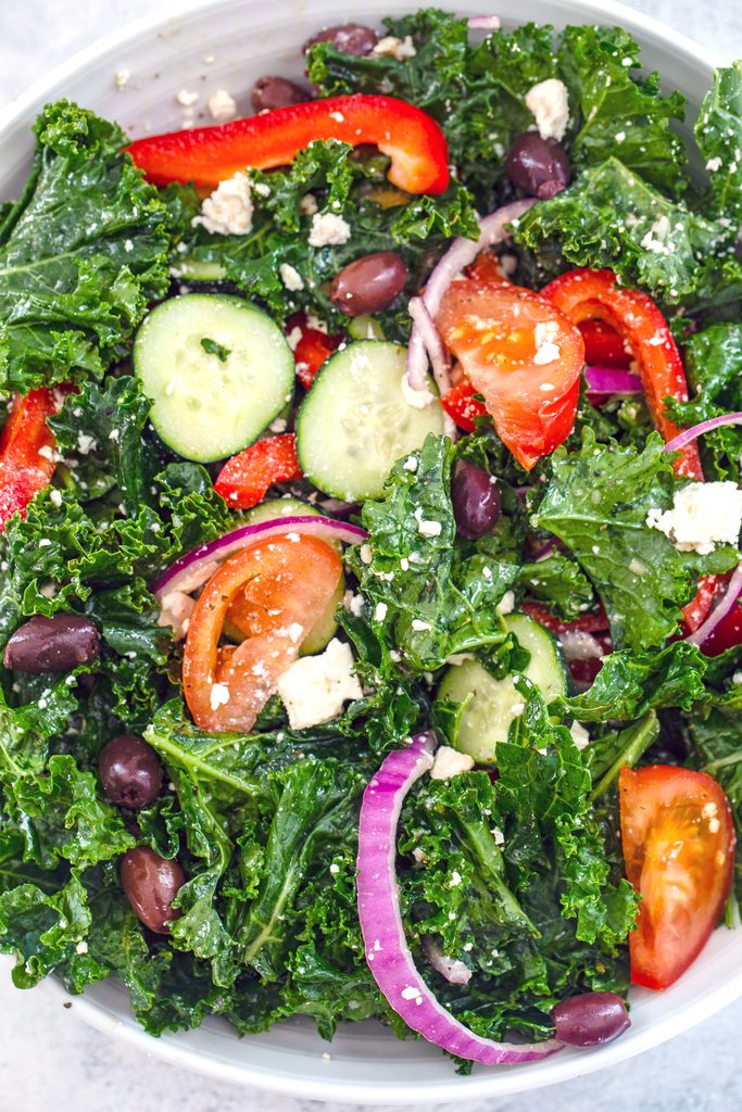 Overhead view of ingredients for kale Greek salad all mixed together in serving bowl