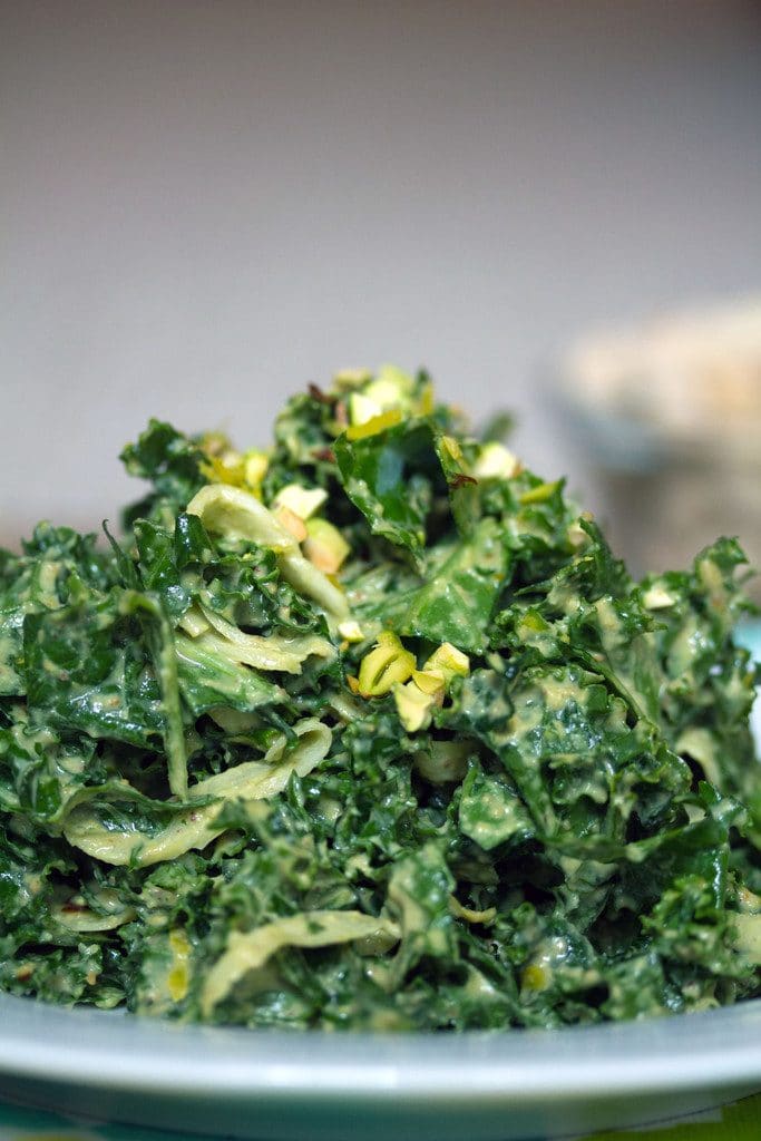 Close-up view of chopped kale and fennel covered in pistachio dressing with lemon zest and chopped pistachios on top