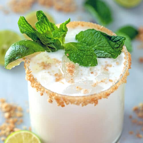 Key Lime Pie Mojito -- This summer cocktail is key lime pie in a glass, complete with fresh mint, a graham cracker rim, and a splash of cream. The only thing missing is the sunny day necessary to enjoy this Key Lime Pie Mojito! | wearenotmartha.com