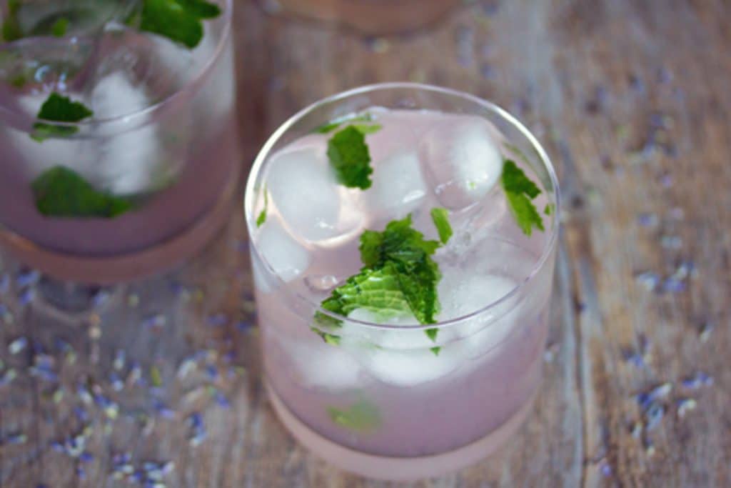 fra ovenfor visning av lavendel lemonade mojito på en tre overflate med tørket lavendel drysset rundt