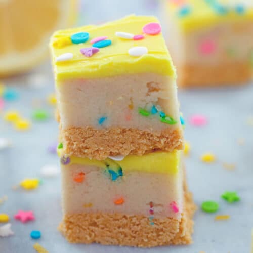 Two lemon cookie dough bars stacked on each other with sprinkles all around