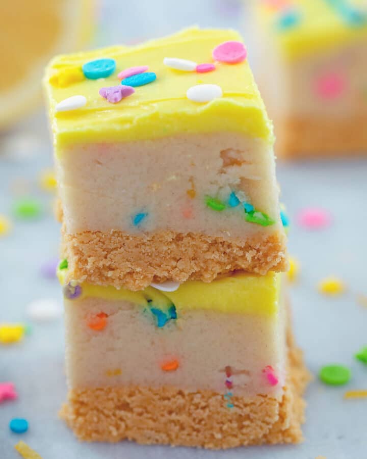 Two lemon cookie dough bars stacked on each other with sprinkles all around