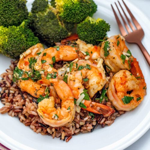 Closeup view of lemon garlic parmesan shrimp over a bed of wild rice with side of broccoli