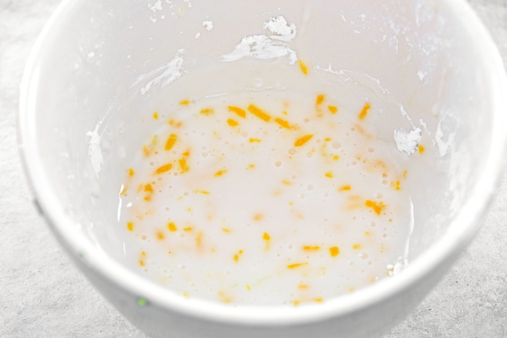 Overhead view of lemon glaze with lemon zest in a mixing bowl