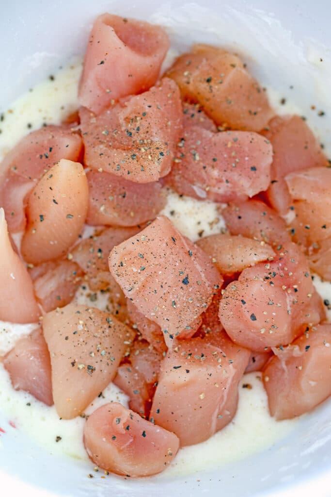 Cubed chicken in bowl with egg whites and cornstarch.