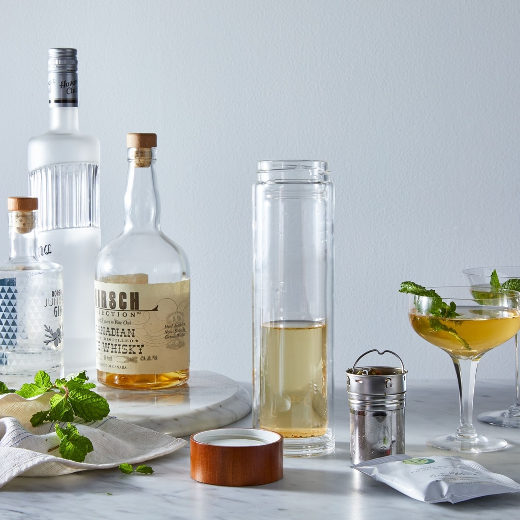 Head-on view of liquor infusion set with various bottles of liquor, glasses of cocktails, and herbs