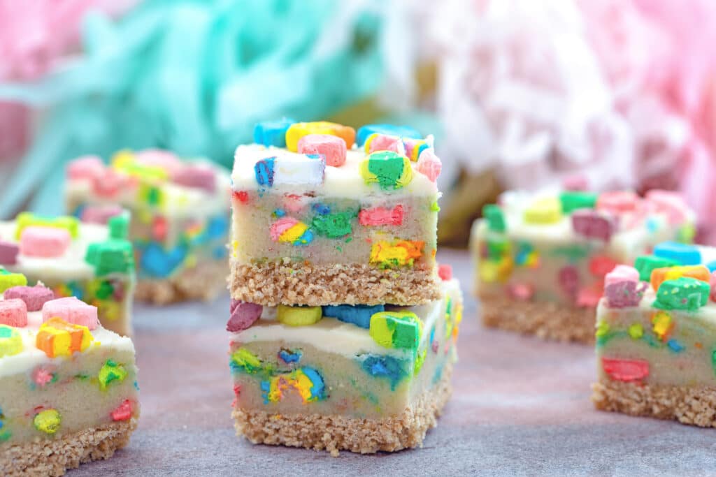 Landscape head-on view of two Lucky Charms cookie dough bars stacked on each other with lots more bars all around
