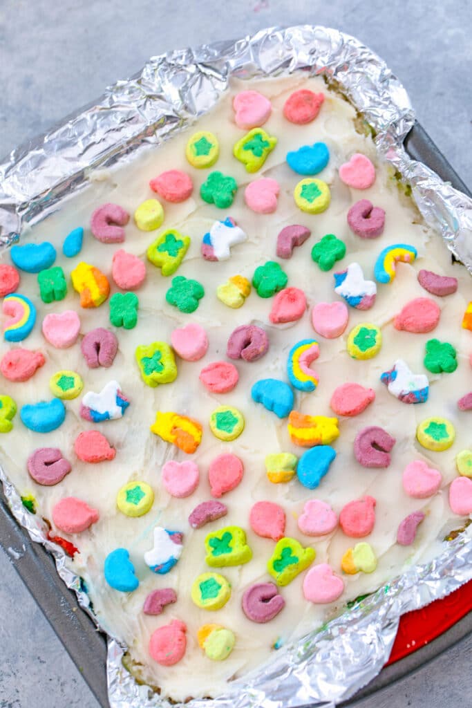 Overhead view of Lucky Charms cookie dough bars in baking pan with marshmallows pressed on top