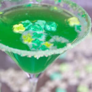 Close-up view of bright green Lucky Charms martini with green marshmallows and cereal rim on glass