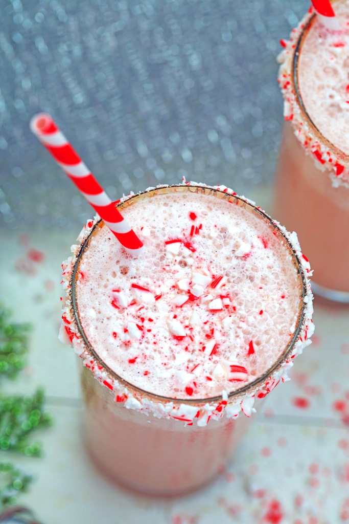 Overhead view of malted candy cane milkshake with red and white striped straw and lots of crushed candy canes