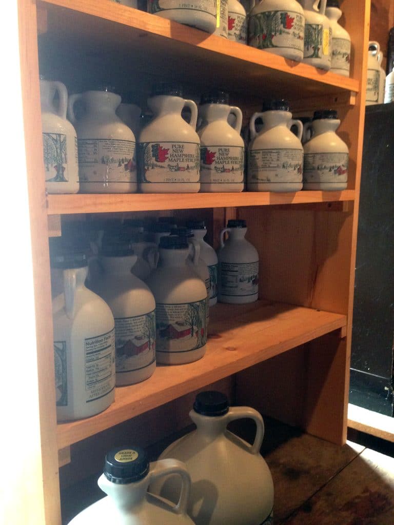 A shelf filled with bottles of Pure New Hampshire Maple Syrup