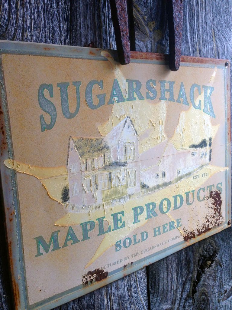 Sign on the front of the sugar shack that says "Sugarshack" and "Maple Products Sold Here"