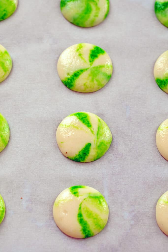 Overhead view of marbled green macarons piped onto baking sheet
