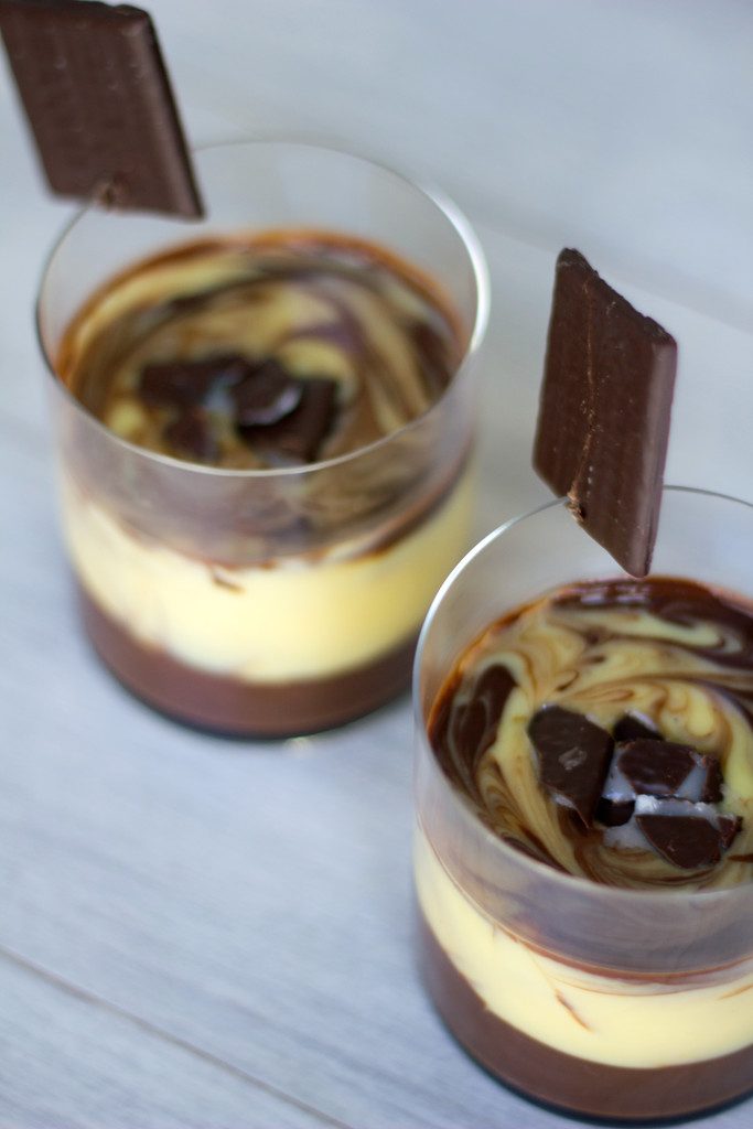 View of two clear glasses of marbled mint-chocolate pudding showing white and brown layers with glasses topped with After Eight mints