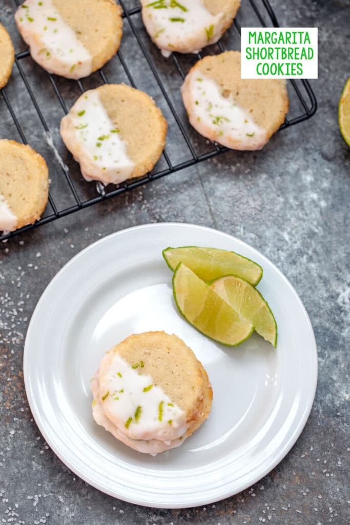 Overhead view of margarita cookies on a plate with lime wedges with more cookies on a rack in background and recipe title at top