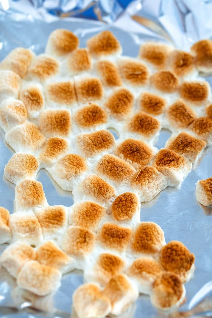 Overhead view of lightly browned toasted marshmallows on a foil-lined baking sheet
