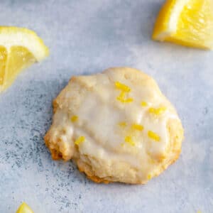 Overhead close-up view of Martha Stewart glazed lemon cookie with lemon wedges and icing in background