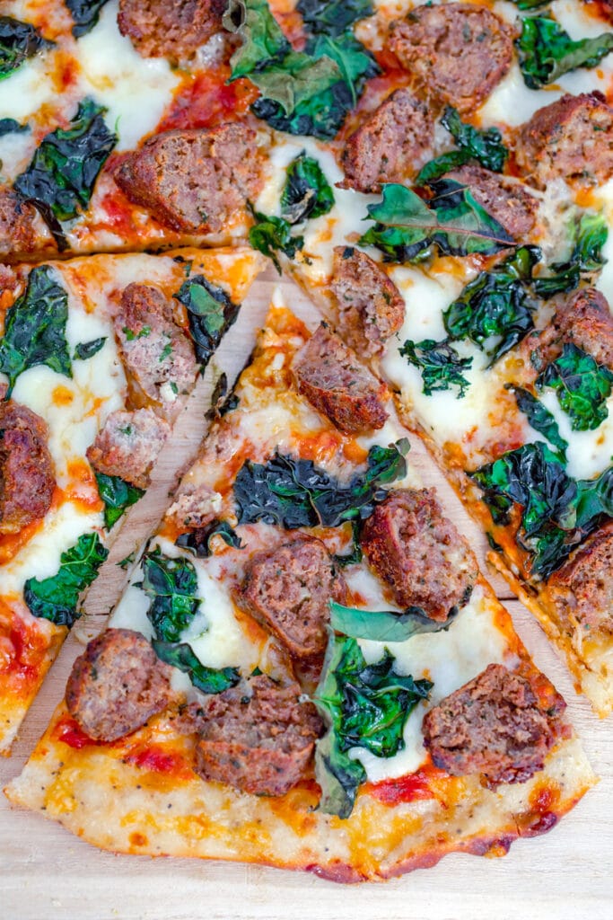 Overhead closeup view of slice of meatball flatbread pulled out from rest of pizza