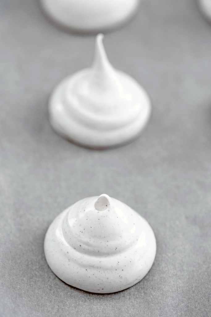 Head-on view of meringue batter piped onto baking sheet ready to go into the oven