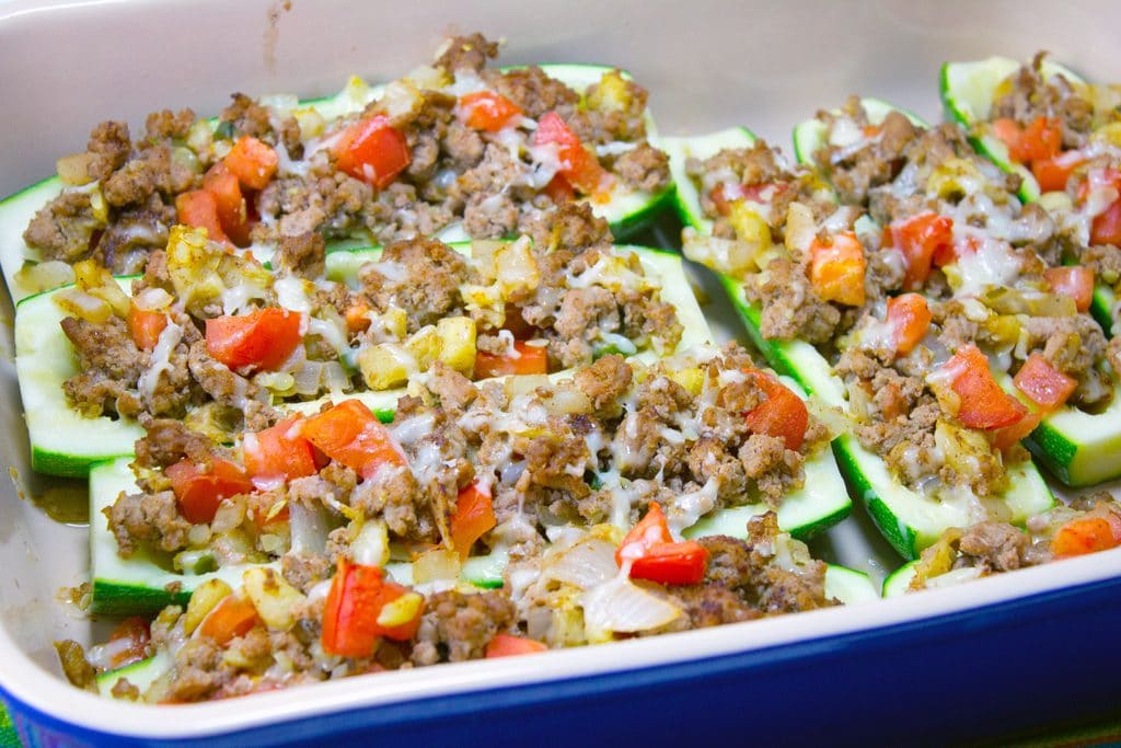 Landscape view of 8 Mexican zucchini boats with turkey and tomatoes in a blue casserole dish