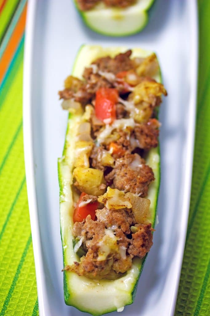 Overhead view of a Mexican zucchini boat with turkey and tomatoes on a skinny white platter