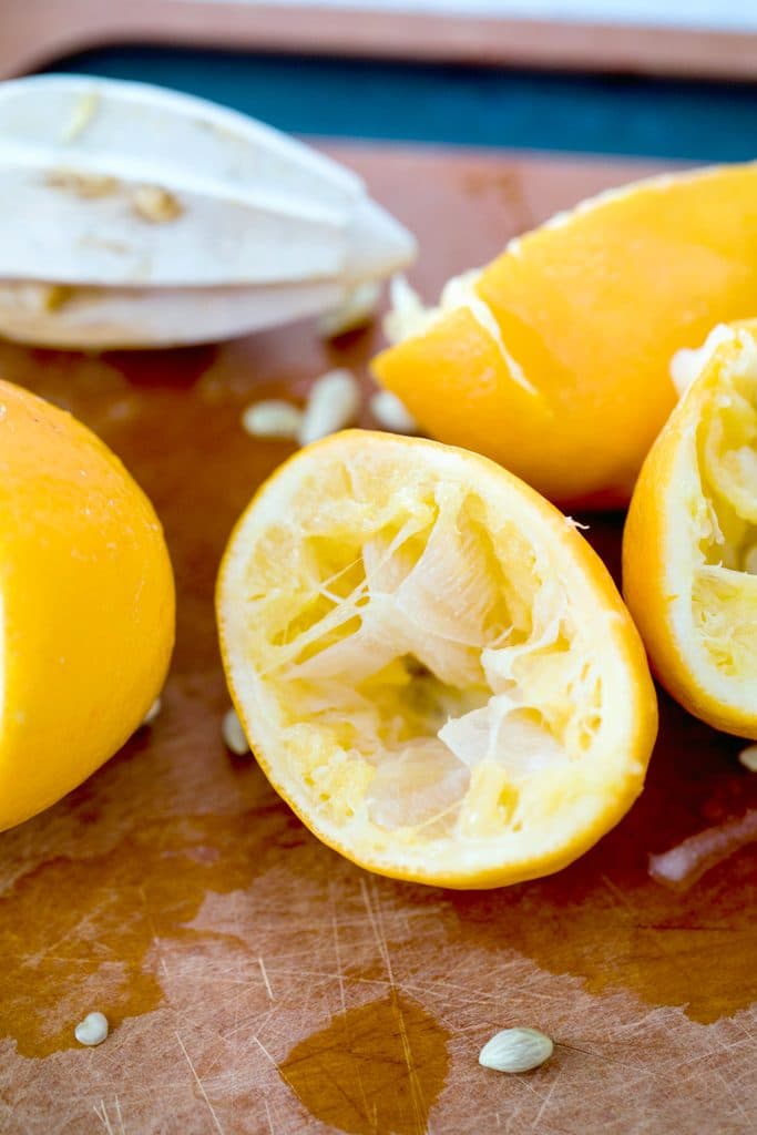 Cutting board with halved juiced Meyer lemons and wooden juicer