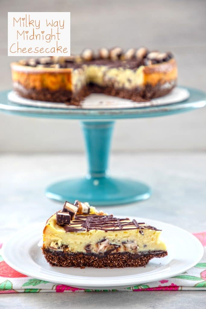 Head- on view of milky way cheesecake with a slice on a white plate and the rest of the cheesecake on an aqua cake stand in the background and "Milky Way Midnight Cheesecake" text at top