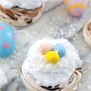 Mini Easter Pavlovas -- These Mini Easter Pavlovas have a chocolate swirled pavlova base and are topped with coconut whipped cream, shredded coconut, and Cadbury Mini Eggs. They make for a fun and delicious Easter dessert, but the mini pavlova base can be made any time of year | wearenotmartha.com