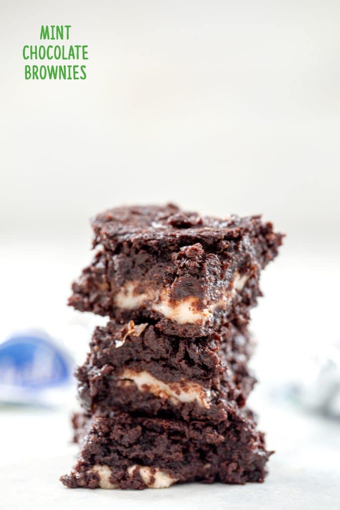 Head-on stack of three mint chocolate brownies stacked on top of each other with peppermint patty wrappers in the background and "mint chocolate brownies" text at top