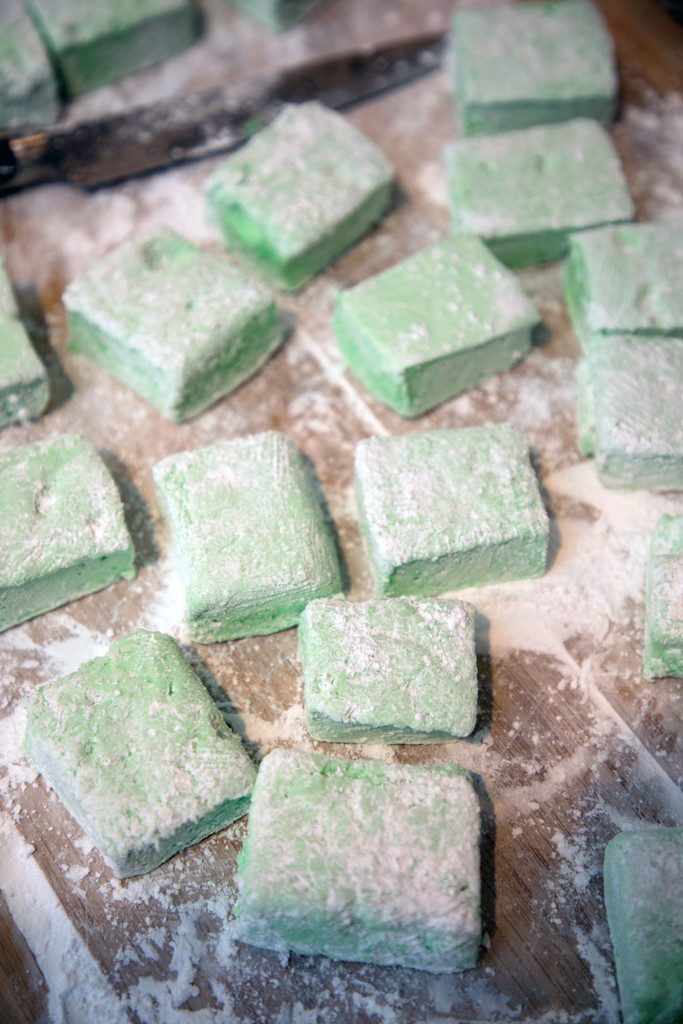 Overhead view of just cut green mint marshmallows sitting in powdered sugar on cutting board