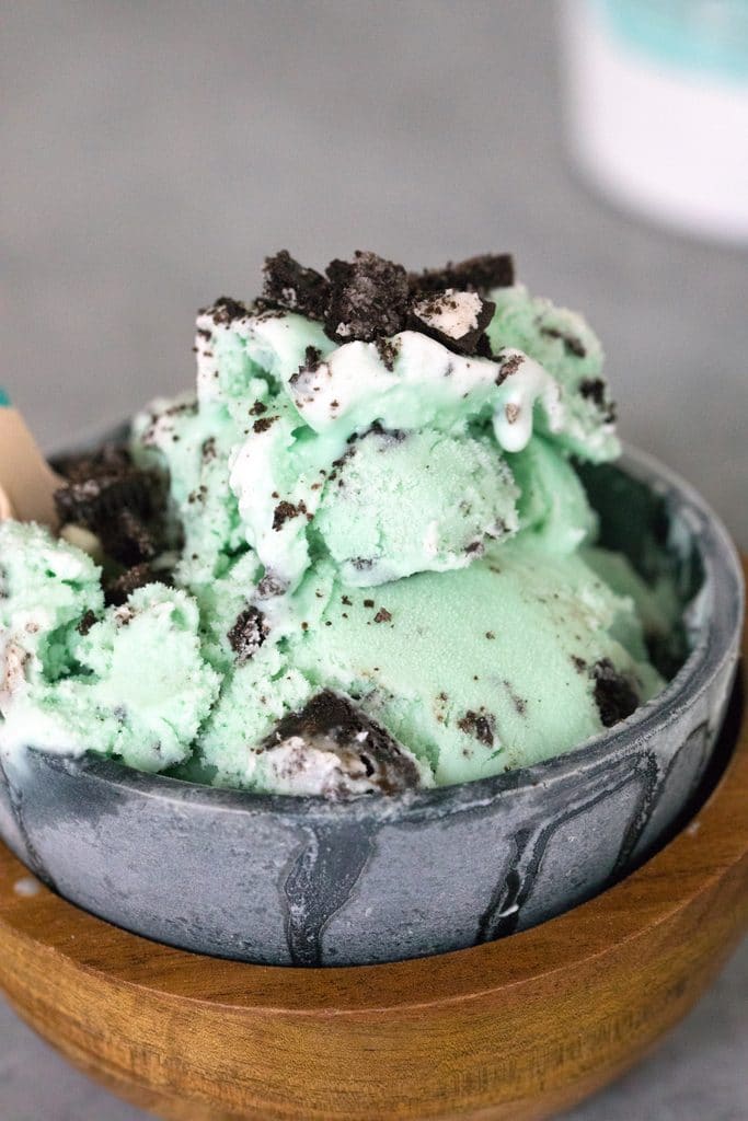 Close-up photo of light green mint oreo ice cream in metal and wood bowls