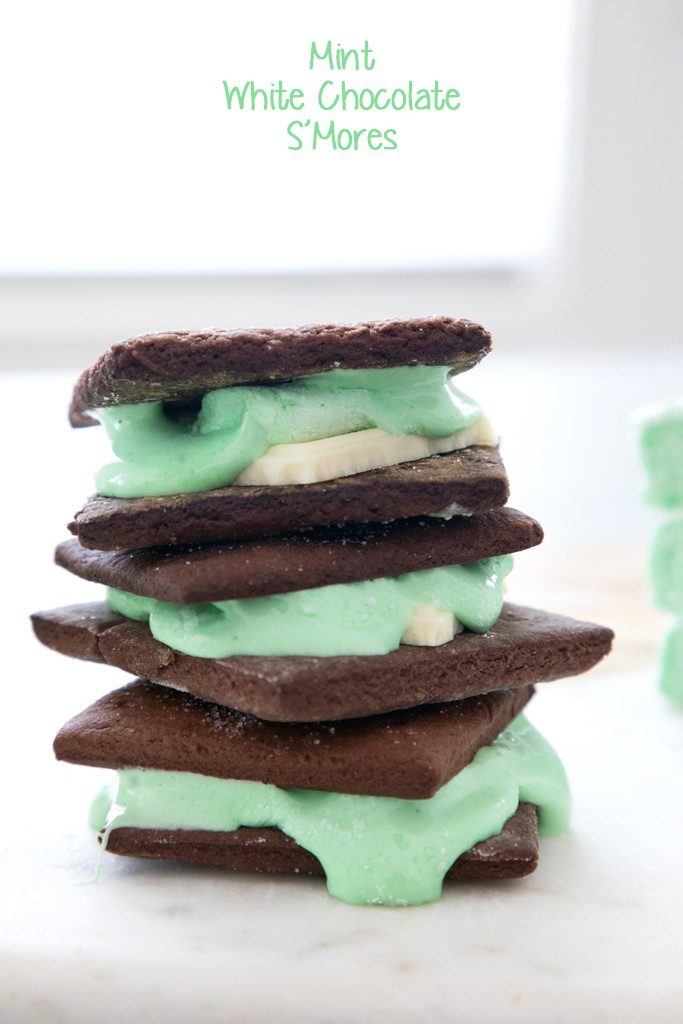 Head-on view of stack of three mint white chocolate s'mores made with chocolate graham crackers and oozing green mint marshmallows with recipe title at top