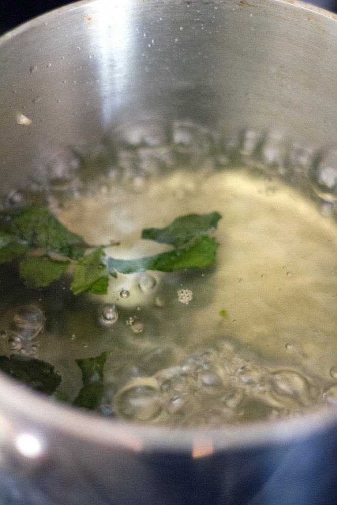 Simple syrup boiling in a saucepan with mint leaves