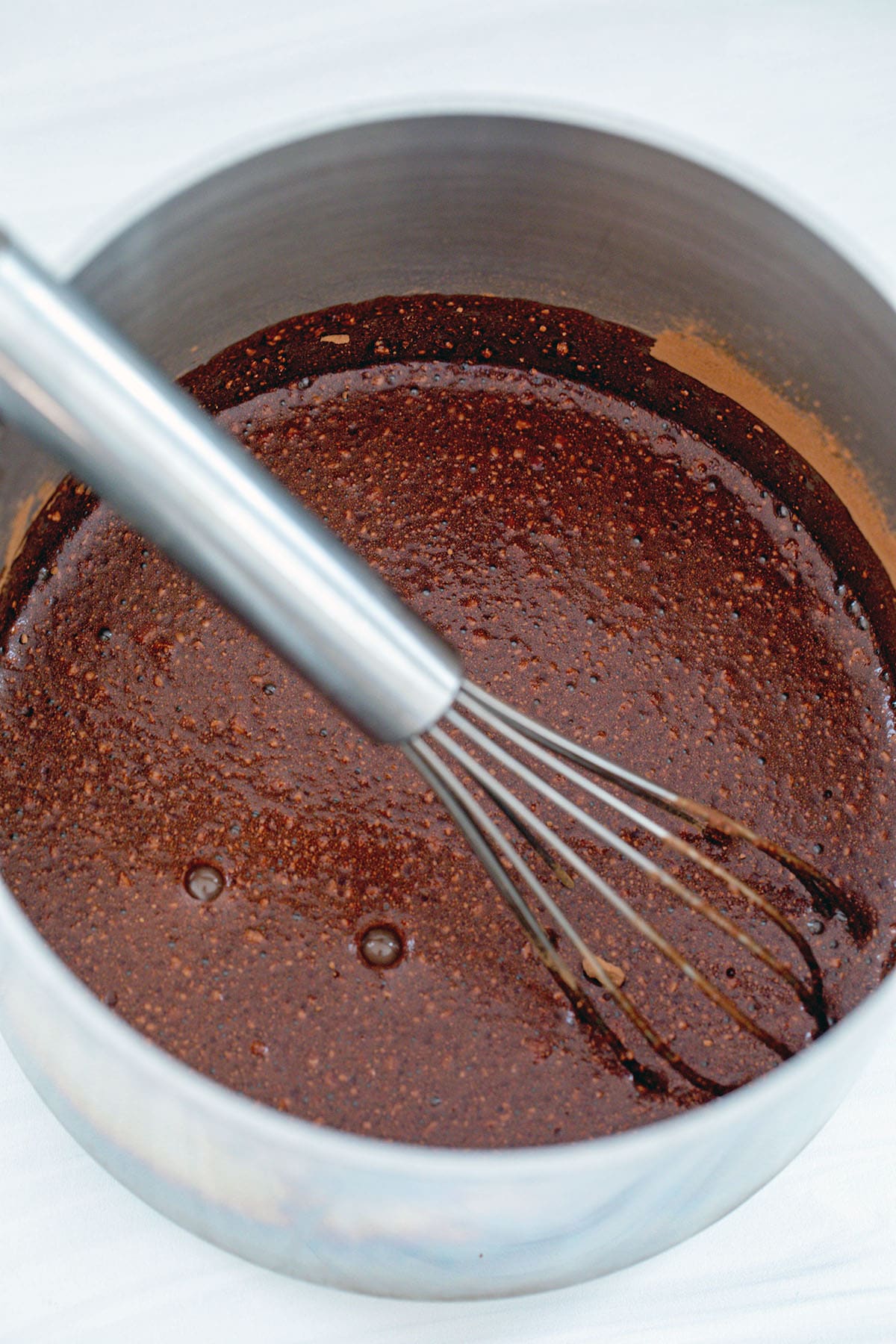 Mocha syrup in saucepan with whisk.